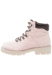 Botín de ante rosa claro con un collar de cuero marrón, ojales metálicos y cordones grises. Presenta una suela de goma blanca y resistente con tracción.