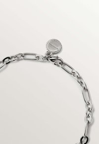 Collar de cadena de plata compuesto por eslabones alargados, con un cierre redondo texturizado que lleva grabado el logo de la marca. Acabado liso y brillante.