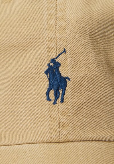 Tessuto beige con logo blu ricamato raffigurante un giocatore di polo a cavallo che tiene un martello alzato.