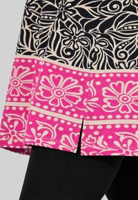 Gonna multi-paternata con una parte superiore floreale nera e crema e una parte inferiore rosa brillante con motivi floreali e a pois.