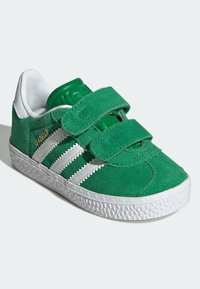 Green suede toddler shoes with white rubber sole, featuring two hook-and-loop straps and three white stripes on the sides.