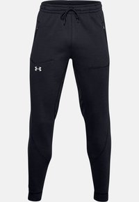 Svarta träningsoveraller av mjukt tyg, med dragsko i midjan, fickor med dragkedja och smalnade ben med elastiska fållar.