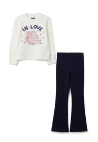 Witte sweatshirt met roze sneakers en de tekst "Verliefd op deze schoenen" in combinatie met eenvoudige zwarte flared broeken.