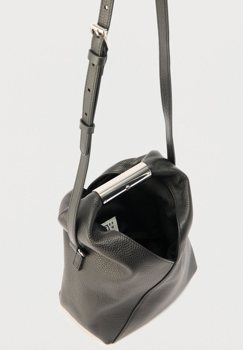 Black leather bucket bag with a textured surface, silver hardware at the top, and an adjustable strap. Interior is black fabric.