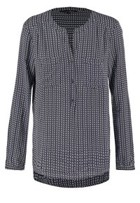 Långärmad blus i marinblått med ett vitt zigzag-mönster, med V-ringning och knappdetalj fram, tillverkad av lätt tyg.