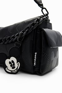 Čierna kožená kabelka sembosovanými oblými vzormi, masívnym reťazovým popruhom a kľúčenku Mickey Mouse ako doplnok. Obsahuje uzáver na prednej klapke.