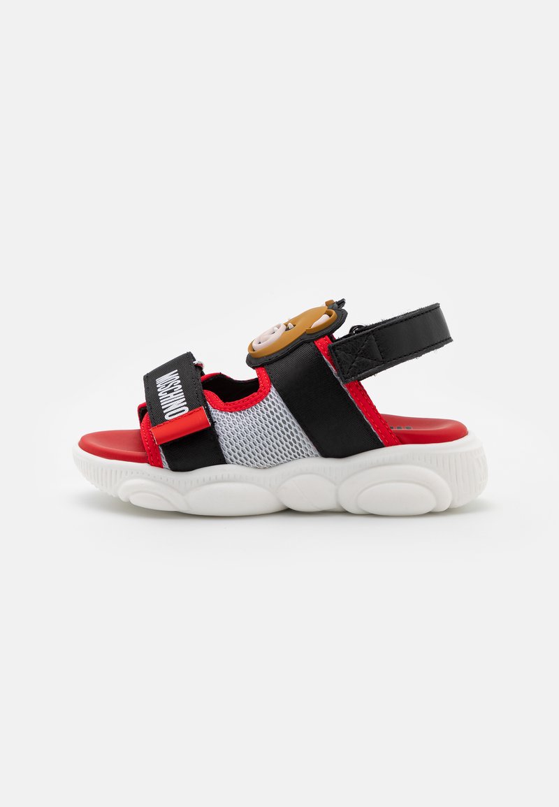 Sandália vermelha e preta com parte superior em malha, tiras ajustáveis e sola almofadada branca. Inclui um detalhe decorativo de personagem na tira.