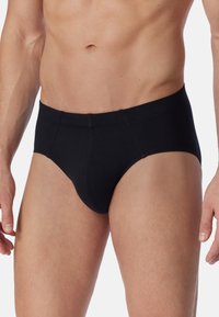 Culottes en coton noir avec une texture lisse, présentant une coupe classique, une taille élastique et des détails de couture minimes.
