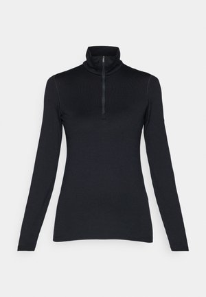 Melnā garām piedurknēm bikses krekls ar augstu apkakli un īsu ar rāvējslēdzēju priekšpusi. Gluda tekstūra ar pieguļošu dizainu un bez redzamām rakstām vai akcentiem.