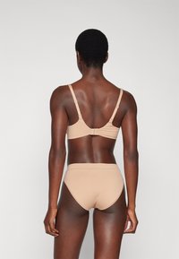 Beige bralette and high-waisted underwear set. Smooth fabric, adjustable straps, and a clasp at the back. Minimalist design with no patterns.