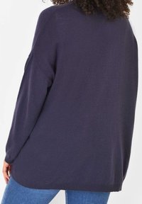 Tmavě modrý, volný pletený svetr s žebrovanými manžetami a lemem. Měkká textura a pohodlný střih s designem se spadlými rameny.