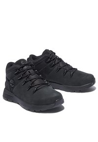 Chaussures de randonnée noires en daim et en mesh, dotées d'un col rembourré, d'une semelle en caoutchouc et d'un système de laçage pour un maintien sécurisé. Logo Timberland visible.