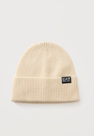 Bonnet en maille côtelée beige avec revers plié et écusson logo noir EA7 Emporio Armani sur le revers.