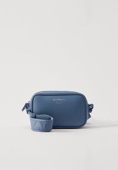 Sac à bandoulière en cuir synthétique bleu avec une surface texturée, de forme rectangulaire, fermeture éclair et une sangle à motifs. Décoré d'un logo en métal.