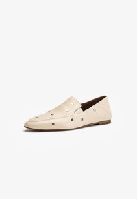 Chaussure à enfiler en cuir crème avec des clous argentés, un bout pointu et un design minimaliste. Texture lisse avec un éclat subtil.
