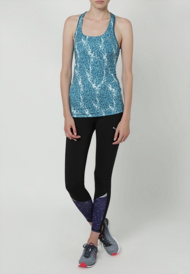 Blå mönstrad atletisk linne med racerback-design, parat med svarta leggings med lila blommönster och grå löparskor.