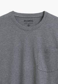 Szara bawełniana koszulka z okrągłym dekoltem, krótkim rękawem i kieszonką na piersi po lewej stronie. Metka na dekolcie mówi "ATLANTIC MEN'S PAJAMAS".