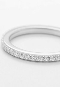 Silberner Ring mit einer glatten Oberfläche und einer Reihe von kleinen klaren Steinen, die entlang einer Kante eingesetzt sind, was ein modernes und elegantes Design zeigt.