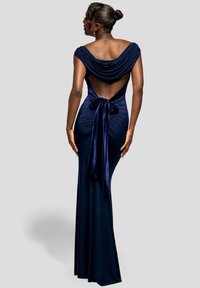 Mørkeblå aftenkjole med draperet halsudskæring, åben ryg og gulvlængde. Rynket stof med bindedetalje bagpå. Blød glans.