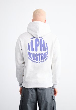 Light gray hoodie with a large purple circular logo reading "ALPHA INDUSTRIES" on the back. Features a drawstring hood and ribbed cuffs.