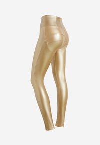 Leggings metallici dorati con vita alta, superficie liscia e design aderente. Presentano tasche posteriori e cuciture curve.