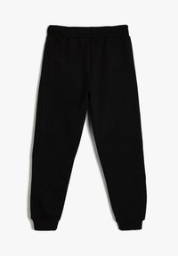 Zwarte joggingbroek gemaakt van zachte stof, met een elastische tailleband en manchetten, een recht model en zonder zichtbare patronen.