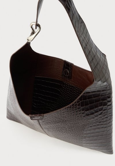 Σκούρο καφέ δερμάτινη τσάντα ώμου με ανάγλυφη υφή κροκό, φαρδιά λουριά, ασημένιο κούμπωμα και ανοιχτό πάνω μέρος που αποκαλύπτει εσωτερική τσέπη και λεία επένδυση.