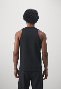 Černý bezrukávový top, bavlněný materiál, kulatý výstřih, hladký zadní díl, přiléhavý střih, doplněný černými šortkami.