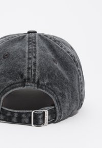Gorra de mezclilla negra con una textura desgastada, una correa metálica ajustable en la parte posterior y una costura en la parte superior.