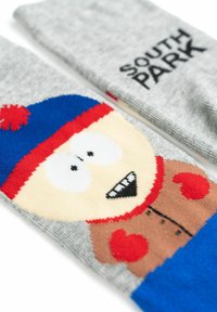 Calze grigie con un personaggio dei cartoni animati dagli occhi grandi, che indossa un cappello rosso con un pompon, un cappotto marrone e dettagli blu. Include il testo "SOUTH PARK".