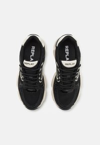 Baskets noires en matière maillée et synthétique, avec des accents crème et une semelle texturée. Logo "REPLAY" sur la languette.