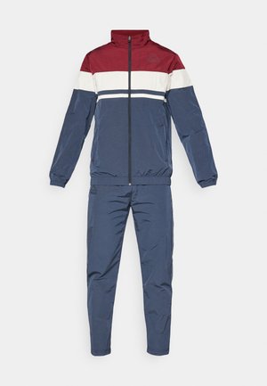 Marineblauwe trainingspak met een bordeauxrode en witte color-blocked jas. Heeft een rits aan de voorkant, hoge kraag en elastische manchetten en tailleband.