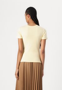 Short-sleeved yellow top with a straight cut, made of soft cotton. It features a classic crew neckline and smooth texture.