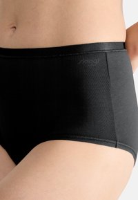 Culottes noires taille haute en tissu lisse, dotées d'une large ceinture et de bords nets. Côté partiellement visible, sans motifs ni graphiques.