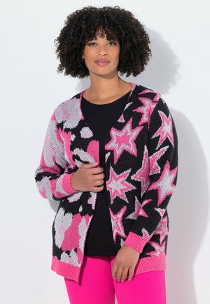 Cardigan avec un fond noir présentant des étoiles roses et blanches ainsi que des motifs floraux. Texture tricotée avec des poignets et un ourlet côtes en rose.