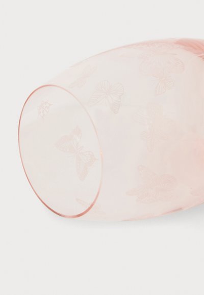 Tasse en verre rose translucide couchée sur le côté avec des motifs délicats de papillons et de coccinelles gravés sur la surface.