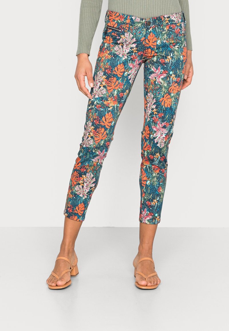 Pantalons à motif floral coloré avec un fond bleu et vert, présentant une coupe ajustée et une longueur cheville, fabriqués dans un tissu léger.