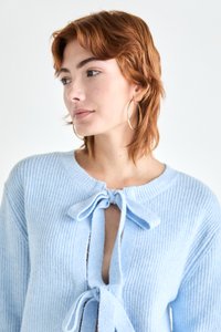 Ljust blå stickad cardigan med rund halsringning, två framknutar och en halvmöjlig design med ribbad textur.