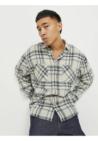 Helles karierter Hemd in Beige, Grün und Marine mit zwei Brusttaschen, Knopfverschluss und langen Ärmeln; aus einem weichen Stoff gefertigt.