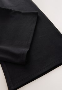 Musta leggingsit, joustavasta ja sileästä kankaasta, istuva malli ja siistit reunat vahvistetuilla saumoilla.