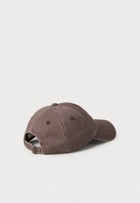 Cappellino da baseball in cotone marrone con visiera curva, cinturino regolabile e dettagli di cucitura sulla corona e sul bordo.