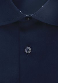 Marineblauwe shirtkraag met een knoopsluiting. De stof is glad met een lichte glans en heeft een klassieke snit met gedetailleerde stiksels.