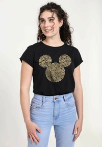 Camiseta negra de manga corta con un diseño de Mickey Mouse en print de leopardo dorado. Combinada con jeans de tiro alto de color azul claro.