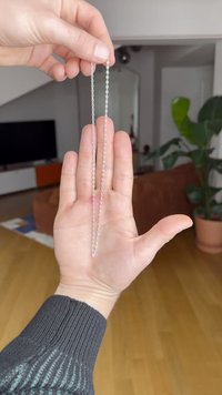 Ασημένια αλυσίδα που κρατιέται στο χέρι, με επιμήκεις οβάλ και στρογγυλούς κρίκους. Το χέρι κρατά την αλυσίδα από δύο άκρα.