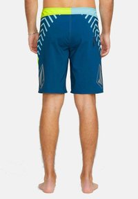 Bañador azul con un diseño estampado en tonos de verde y gris, con cintura ajustable con cordón y bolsillo lateral con cremallera.