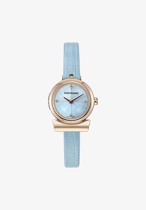 Reloj redondo con correa de cuero texturizado en cocodrilo de color azul claro, caja de oro rosa y esfera de madreperla azul. Presenta marcadores de hora dorados.