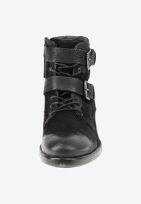 Botín negro de cuero hasta el tobillo con punta redonda, cordones en la parte delantera y dos correas anchas texturizadas con hebillas de metal cruzando la parte superior.