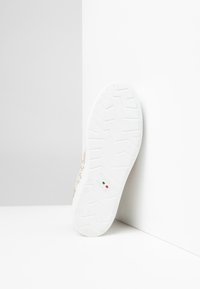 Sneaker bianca con suola in gomma testurizzata e dettagli decorativi. Presenta un logo impresso "Nico Giardini" e un dettaglio della bandiera italiana.