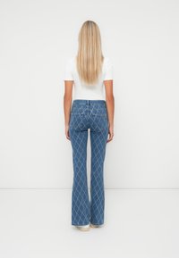 Blauwe flared denim jeans met een diamanten patroon, met een middelhoge taille en een aangesloten silhouet rond de heupen.