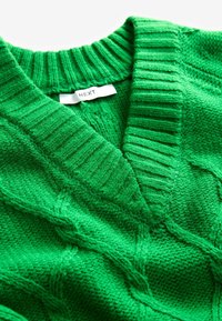 Maglione verde lavorato a maglia con scollatura a V, caratterizzato da una texture a costine e un intricato motivo a trecce. L'etichetta del marchio riporta "NEXT".